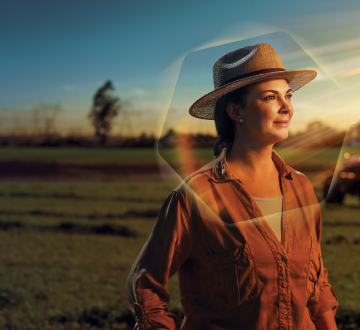 Foto de mulher no campo olhando para o horizonte.